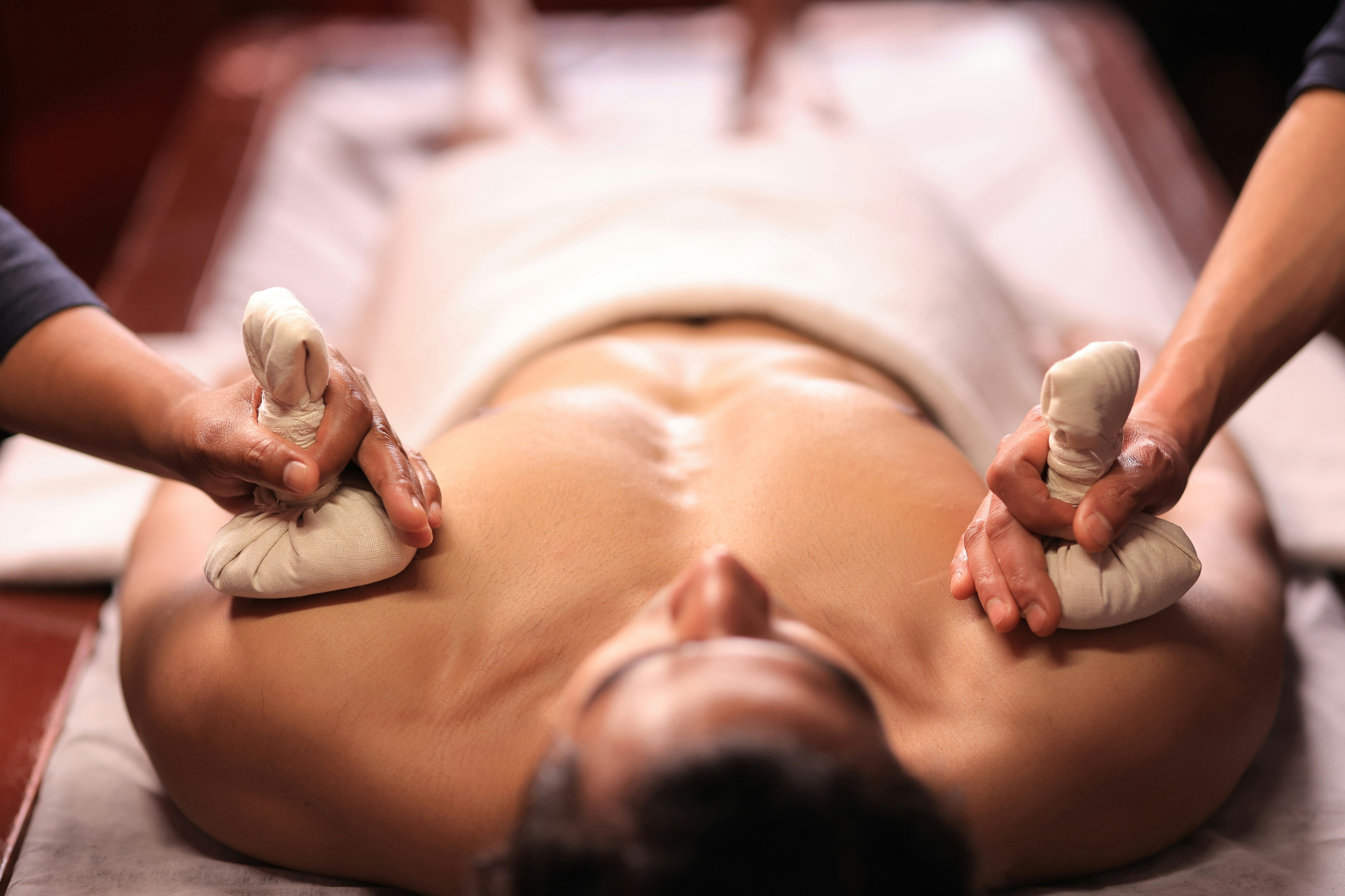 Traditional herbal bolus massage performed by two therapists